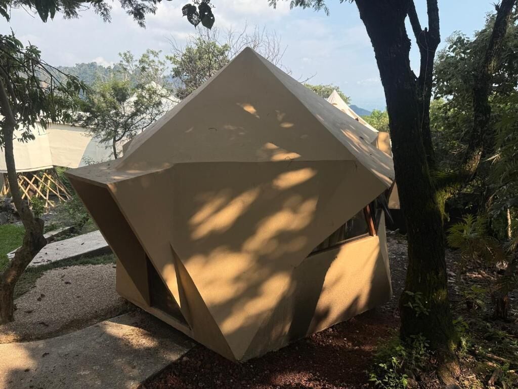 A geometric tent-like structure in a forested area.