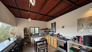 A modern kitchen with a bar area, a dining table, and chairs. - Gaiatri Holistic Glamping (Tepoztlán)