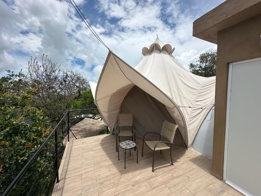 A tent with two chairs and a table on a wooden deck.