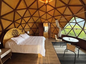 Una habitación tipo tienda con una cama, una mesita y una silla.