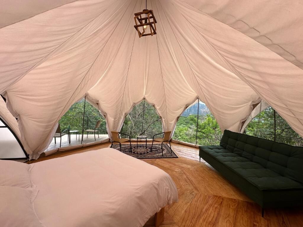 Un hébergement sous tente comprenant un lit, un canapé et offrant une vue sur la verdure.
