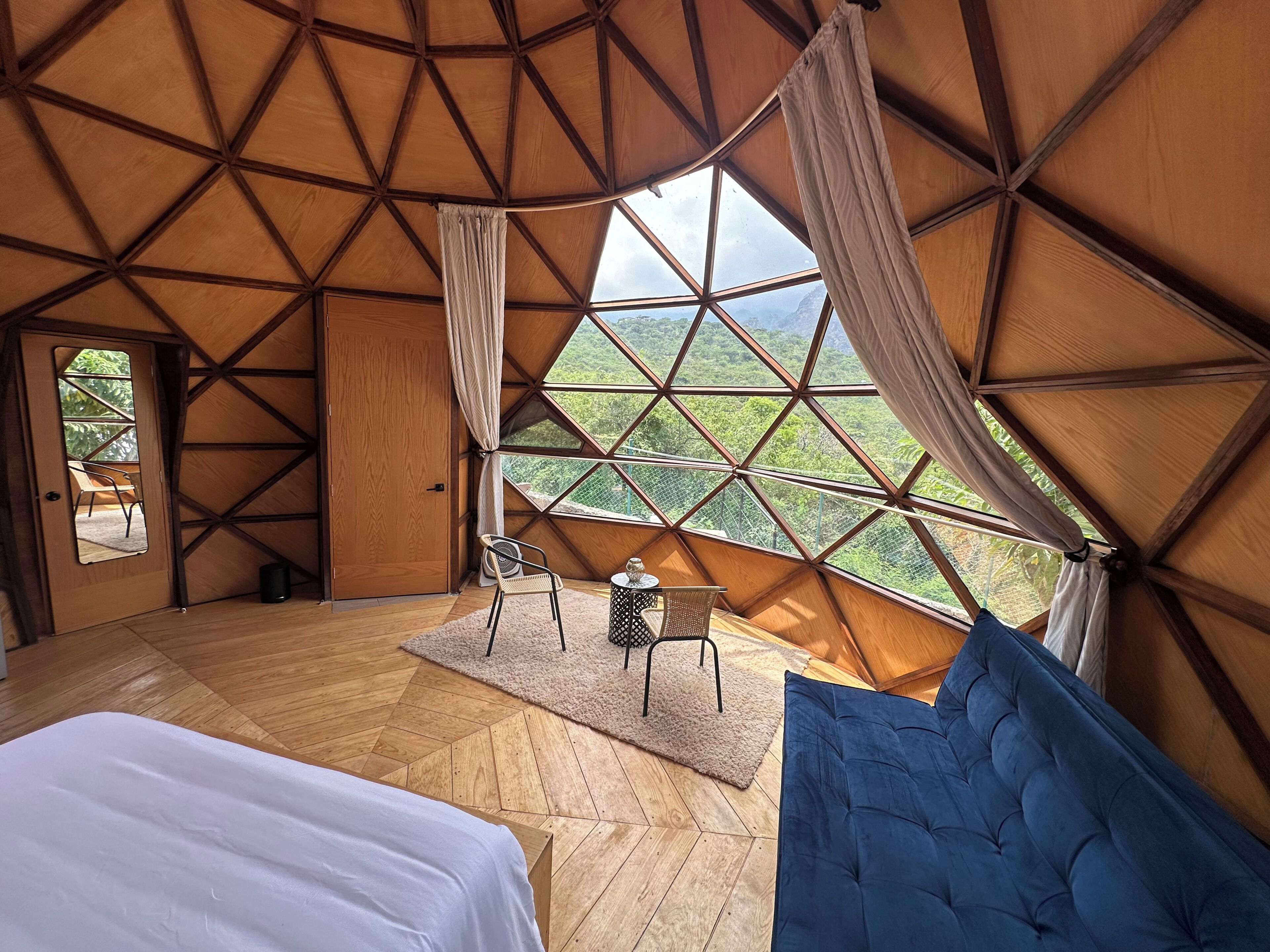 Une pièce avec une grande fenêtre, un lit, une chaise et une petite table.