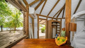 A wooden table with a fruit basket, a beach view, and a covered area with wooden beams. - Domaine De L'Anse Noire, right on the water (Les Anses-d`Arlet)