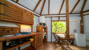 A rustic kitchen with wooden cabinets, a wooden table, and a window with a view of greenery. - Domaine De L'Anse Noire, right on the water (Les Anses-d`Arlet)