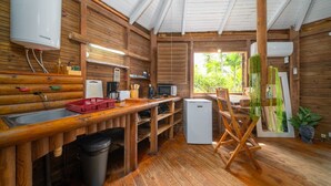 A compact kitchen with wooden walls, a sink, a refrigerator, and a dining area with a table and chairs. - Domaine De L'Anse Noire, right on the water (Les Anses-d`Arlet)