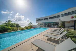 Una piscina con sedie a sdraio e un edificio con ampie finestre.