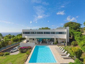 A modern two-story building with a swimming pool and lounge chairs.