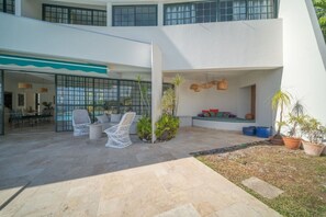 A modern outdoor patio with seating, a dining area, and potted plants.