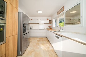 A modern kitchen with white cabinetry, a built-in oven, and a large window providing natural light.