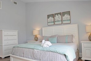 A bedroom with a bed, nightstands, a dresser, and wall art. - Barrier Dunes 542 - 55 - Relax N' Moore (Port St. Joe)