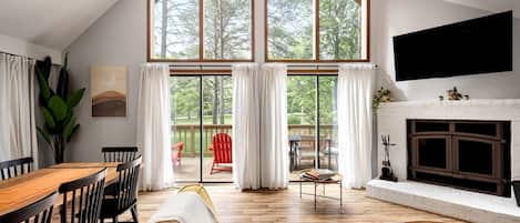 A spacious living room with a large window, a fireplace, and a dining area.