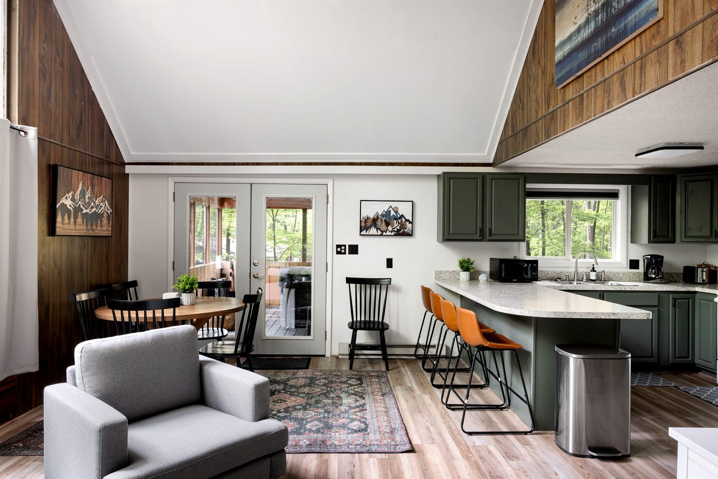 Een moderne keuken met een eethoek, barstoelen en een grijze bank.