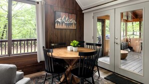 Un comedor con una mesa y sillas de madera, un cuadro en la pared y vistas al exterior.