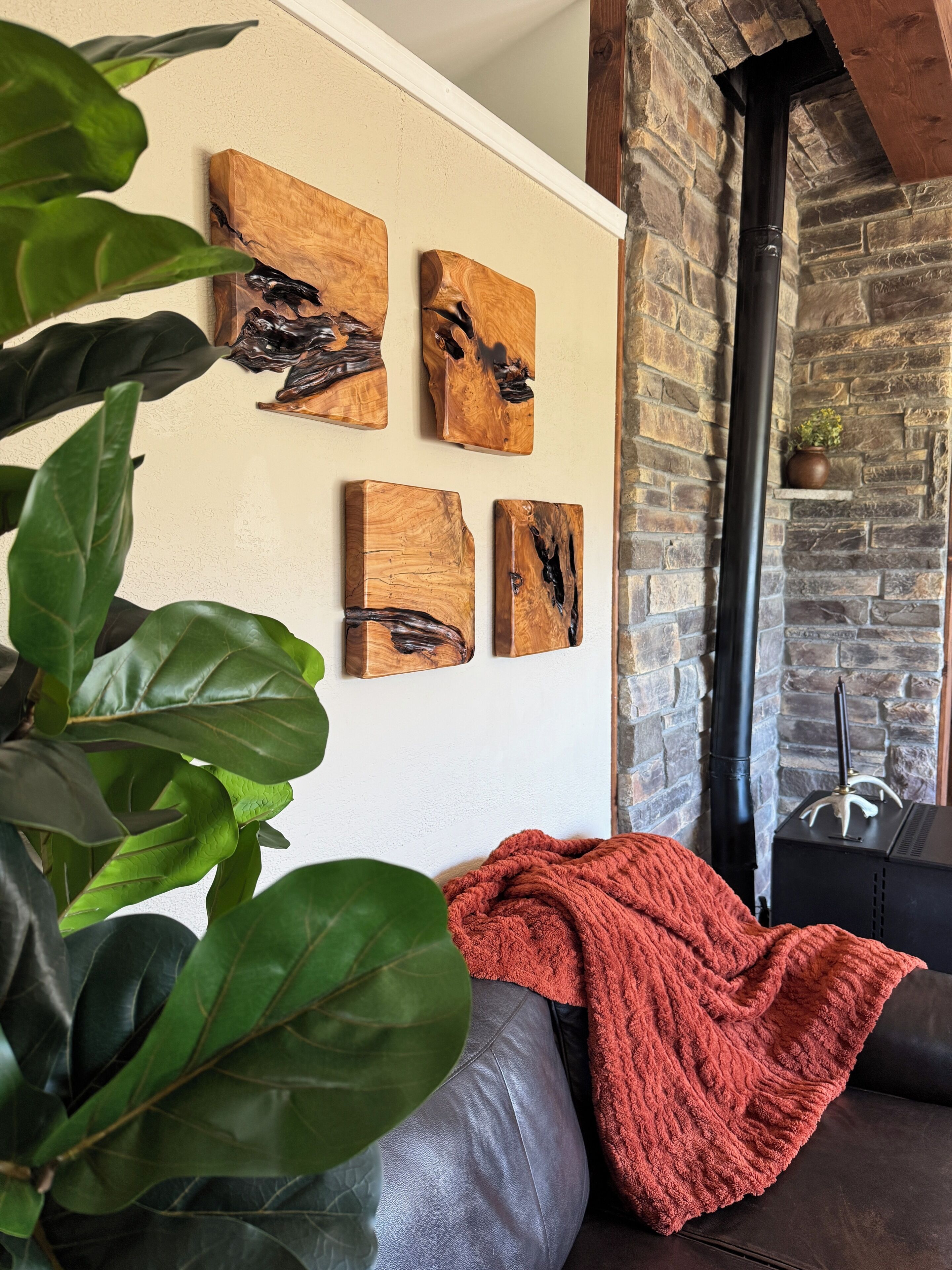 A room with a stone wall, a fireplace, and four wooden art pieces on the wall.
