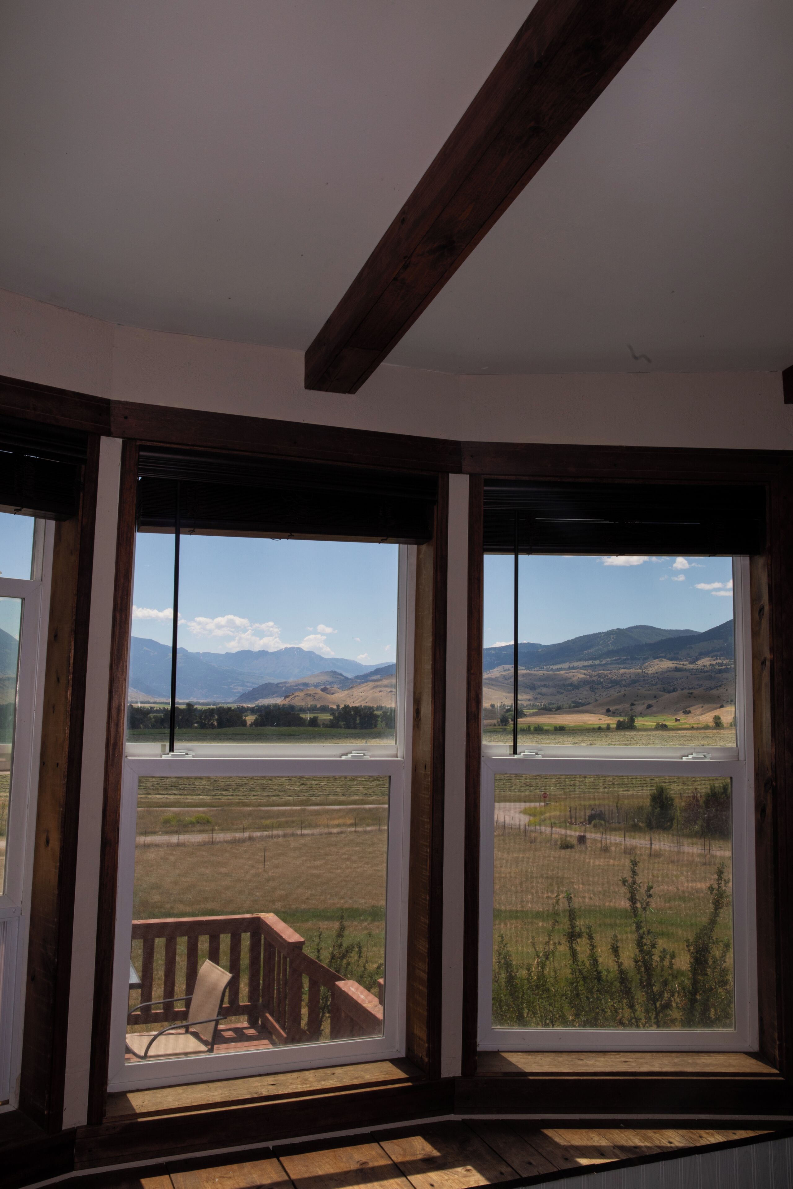 A room with large windows offering a view of a landscape with mountains and a river.