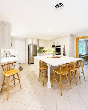 A modern kitchen with white cabinetry, stainless steel appliances, and a central island with stools. - The Park House, 1.8mi to Square, VelvetDitchVillas (Oxford)