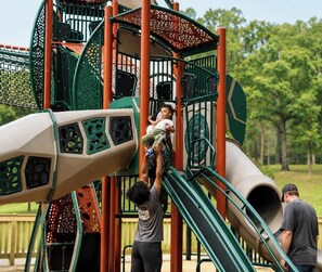 Ein Spielplatz mit Rutsche, Klettergerüsten und einem Netzbereich.