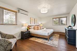 A bedroom with a bed, bedside tables, a dresser, a mirror, and a chandelier. - Spruce Valley Farm Retreat (Fort Erie)