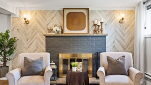 Una sala de estar moderna con dos sillones, una chimenea y paneles decorativos en la pared.