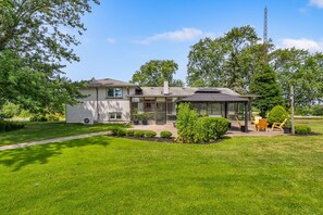 A two-story house with a covered patio, a lawn, and a satellite dish. - Spruce Valley Farm Retreat (Fort Erie)