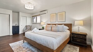 Un dormitorio con una cama de madera, mesitas de noche, una lámpara de techo y una ventana con persianas.