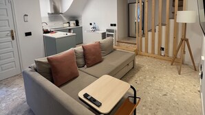 Una sala de estar moderna con un sofá gris, una mesa de madera y un televisor montado en la pared.