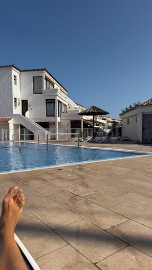 Zona de piscina amb solàrium enrajolat, escala cap a un edifici i filera de gandules.