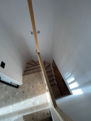 Un escalier en colimaçon avec des marches en bois et une rampe en bois, menant à un étage supérieur.