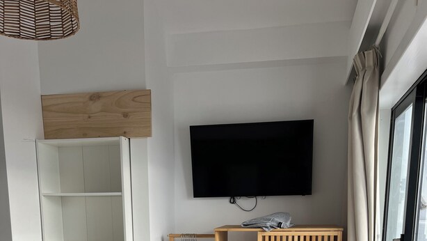 Un dormitorio con cama, armario, televisor y puerta corrediza de vidrio.