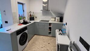 Una cocina compacta con lavadora integrada, microondas y tostadora.