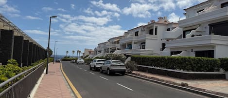 Une rue résidentielle bordée de maisons modernes, avec un ciel dégagé et des voitures garées.