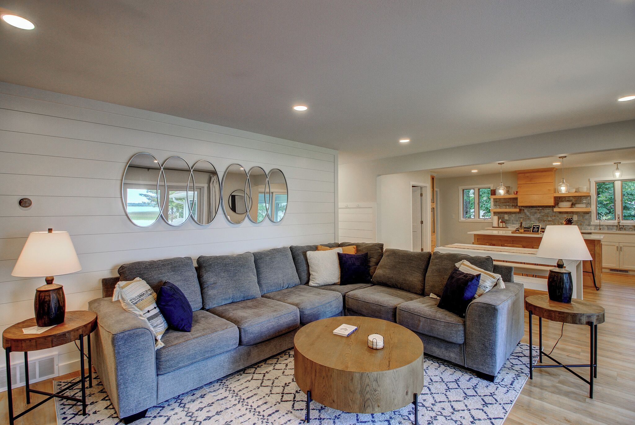 A modern living room with a sectional sofa, a coffee table, and a kitchen in the background.