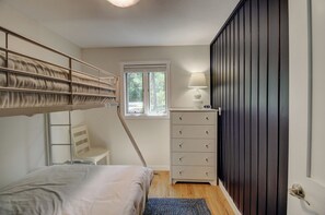 A bedroom with a bunk bed, a desk with a lamp, a dresser, and a window with a view of trees. - Stunning Sunset Views on Round Lake - 3BR Lakefront Cabin with Sauna (Brainerd)