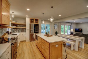 A modern kitchen with wooden cabinets, stainless steel appliances, and a central island. - Stunning Sunset Views on Round Lake - 3BR Lakefront Cabin with Sauna (Brainerd)