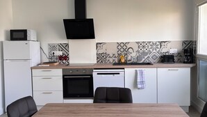 Una cucina moderna con un tavolo da pranzo, sedie nere, forno a incasso, microonde e macchina del caffè.