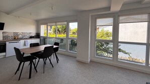 Una cucina moderna con zona pranzo, ampie finestre e vista sul verde.