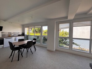 Eine moderne Küche mit Essbereich, großen Fenstern und Blick ins Grüne.