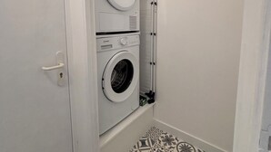 Una lavanderia con due lavatrici affiancate, una porta e piastrelle decorative.