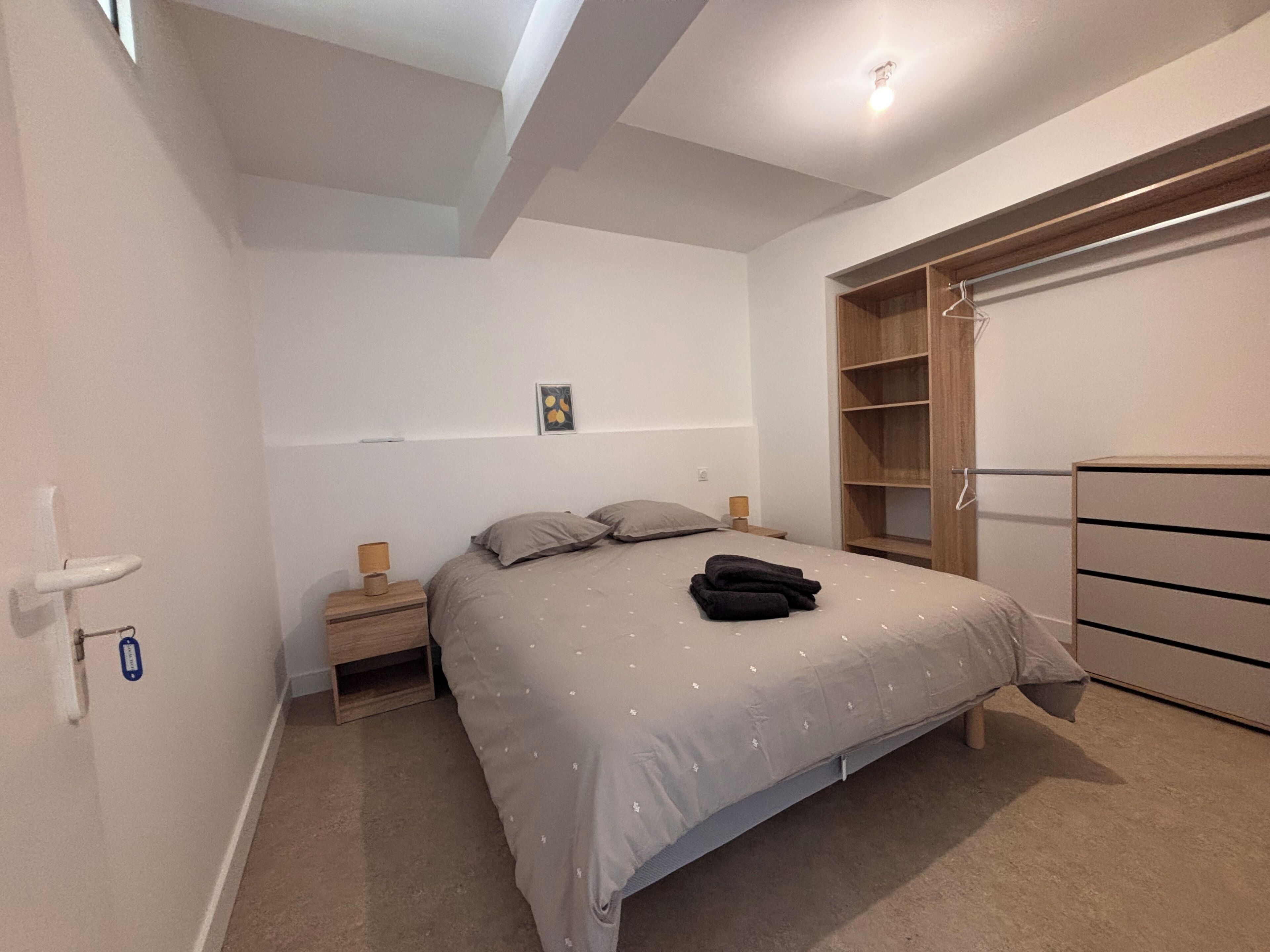 Ein Schlafzimmer mit einem Bett, Nachttischen, einem Kleiderschrank und einer Deckenleuchte.