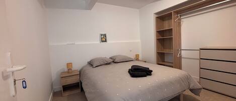 A bedroom with a bed, bedside tables, a wardrobe, and a ceiling light.