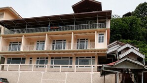 A multi-story hotel with balconies, a covered walkway, and a staircase leading to an upper level.