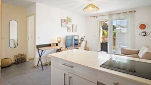 A modern kitchen with a central island, a dining area with a table and chairs, and a living area with a sofa. - Rosalia Apartment - Tropical Charm in Martinique (Fort-de-France)