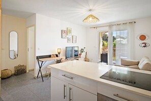 Eine moderne Küche mit einer zentralen Kochinsel, einem Essbereich mit Tisch und Stühlen sowie einem Wohnbereich mit einer Couch.