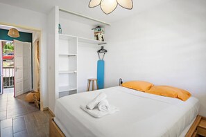 Ein Schlafzimmer mit einem Bett, einem Kleiderschrank, einem Hocker und einer Pendelleuchte.