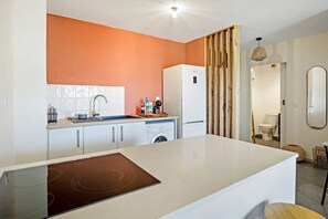 A modern kitchen with a built-in oven, a washing machine, and a refrigerator. - Rosalia Apartment - Tropical Charm in Martinique (Fort-de-France)
