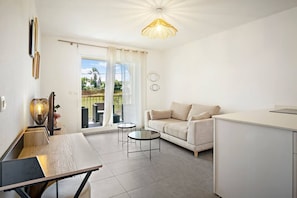 A modern living room with a sofa, a coffee table, and a dining area with a table and chairs. - Rosalia Apartment - Tropical Charm in Martinique (Fort-de-France)