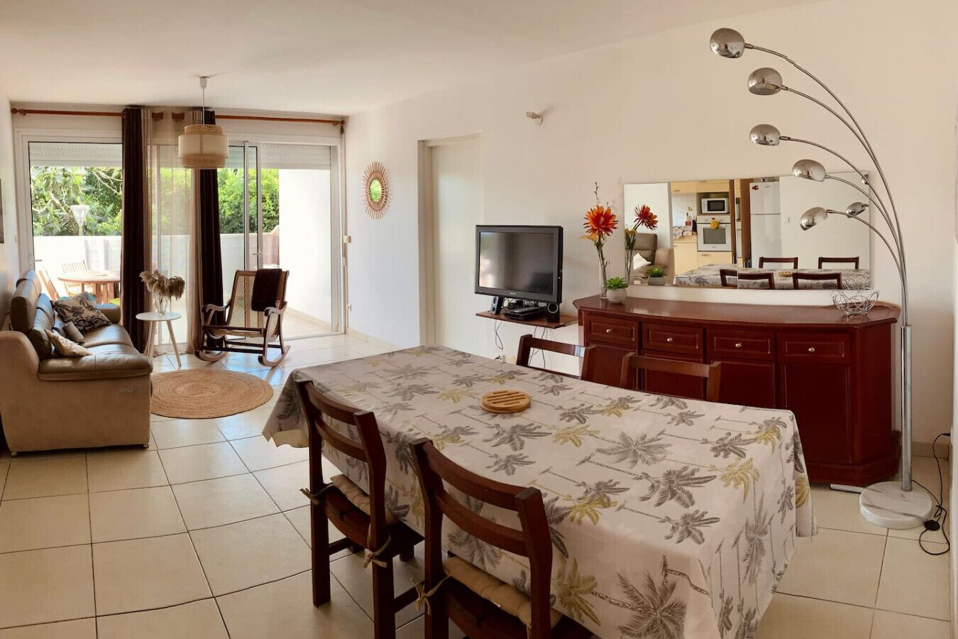 Ein Wohnzimmer mit einer Couch, einem Esstisch mit Stühlen, einem Fernseher und einer Küchenzeile mit einer Mikrowelle.