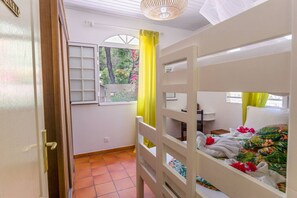 A room with a bunk bed, a window with a view of greenery, and a door with a handle.