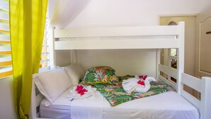 A bunk bed with white bedding, a floral pillow, and a towel with flowers. - Yellow Beach Villa - Creole-style house on the beach (Le Diamant)