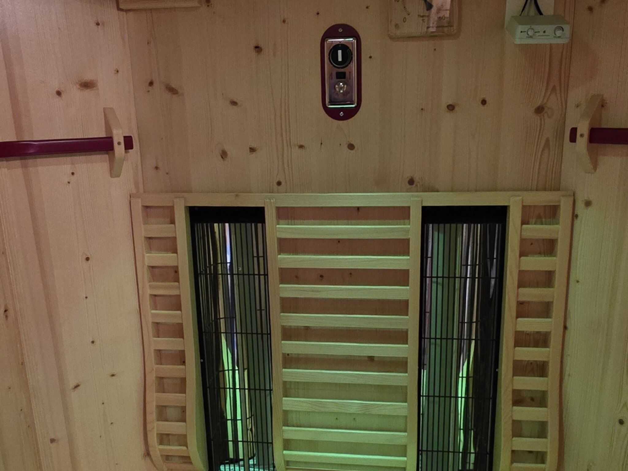 A wooden interior with a central ventilation system and two windows with metal bars.